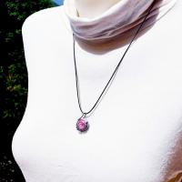 Ce collier pendentif est un cabochon en verre de couleur rose chamarré de noir et blanc