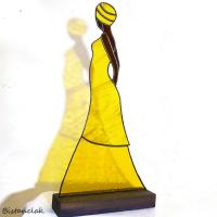 Cette déco vitrail artisanale représente une africaine en robe jaune.