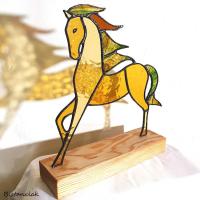 cette décoration vitrail à poser représente un cheval en verre coloré ambre et vert.